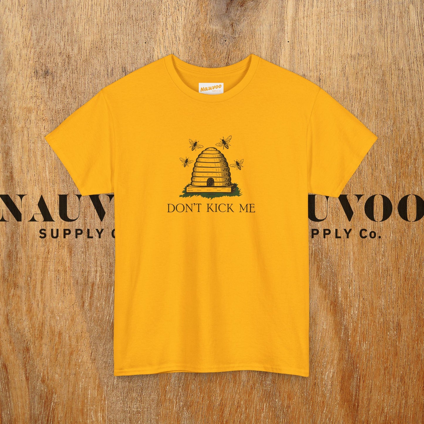 Yellow t-shirt with a bee hive and 'Don't Kick Me' text on a wooden background