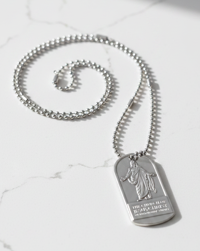 A silver-toned dog tag pendant necklace with a Christ engraving with the name of the Church of Jesus Christ of Latter-day Saints. Features a ball chain.