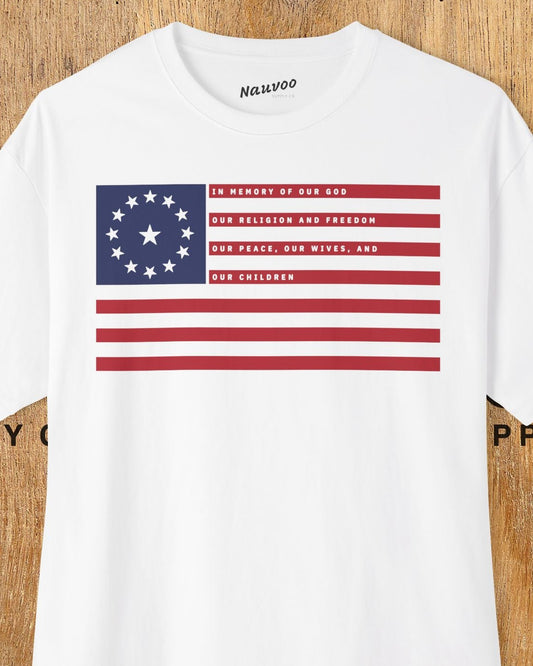 A white oversized t-shirt with a boxy fit featuring an LDS design of the American flag with a central star, displayed against a wooden background.