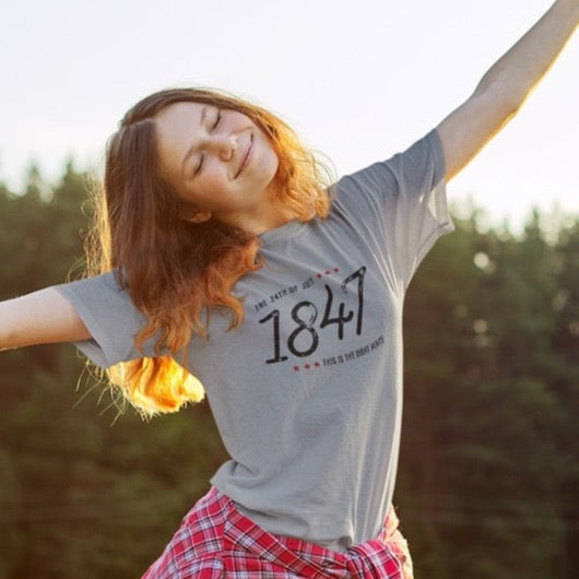 Young woman wearing a gray Pioneer Day t-shirt with 1847